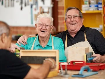 A volunteer helping a senior with woodworking