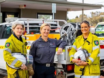 Three female firefighters standing in front of a vehicle