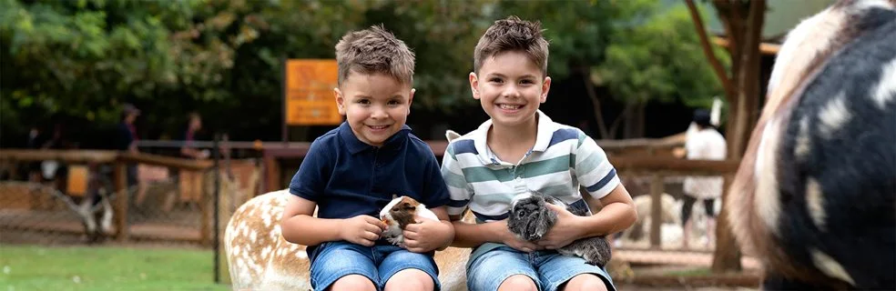 Two young boys each holding a guinea pig