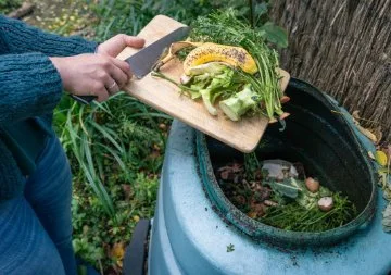 a lady scraping food scraps into a compost bin