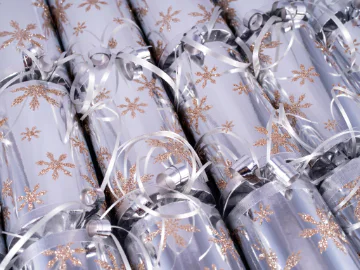 A row of four silver Christmas crackers with gold snowflakes on them