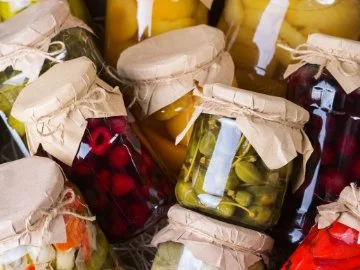 A group of various fruits and vegetables in sealed jars.