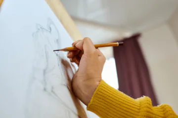 A person creating a still life drawing using pencil.