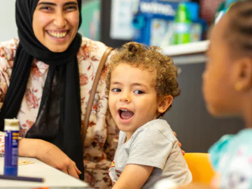 Young children and a parent in a library space smiling