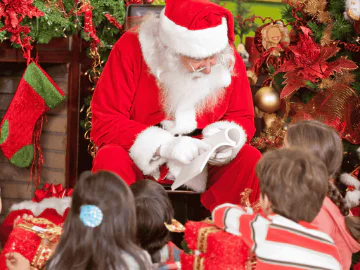 Santa Claus reading a book to a group of children in front of Christmas decorations