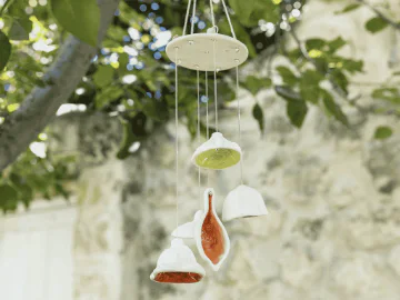A clay windchime hanging from a tree