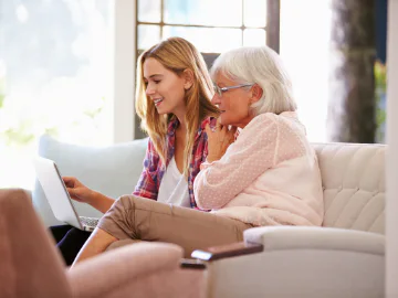 A young person helping a senior on a computer