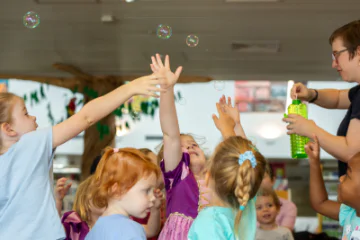Children reaching for bubbles in a library