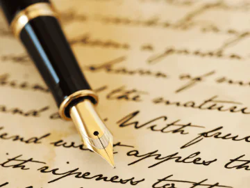 A caligraphy pen resting on a page of handwriting