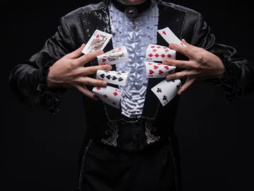 A person in a magician costume holding some playing cards between each finger