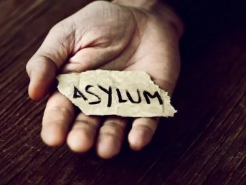 A hand holding a torn piece of paper that says 