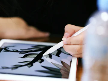 A person using an apple pen to draw a vine on an ipad
