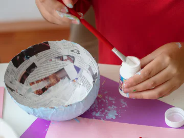 An artist painting a paper mache bowl