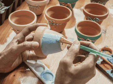 An artist holding a plant pot and painting it