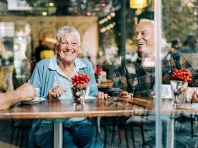 A family of four sit on a picnic table in the Swan Valley with two water birds nearby