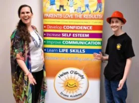 A lady and a boy standing beside a poster