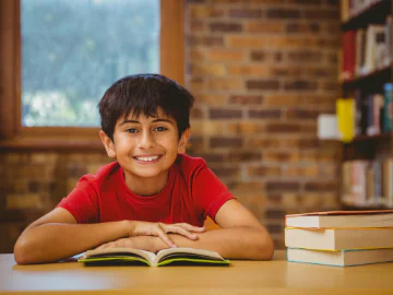 A young boy smiles while reading a book