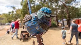 2025's winner standing next to his blue wren metal artwork