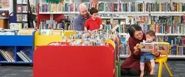 Two parents and two children read books in the children's section of Ballajura Library
