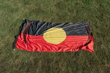 The Aboriginal flag laid out on grass.