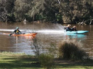 A motorboat and a kayak speed down the Swan River at the Avon Descent