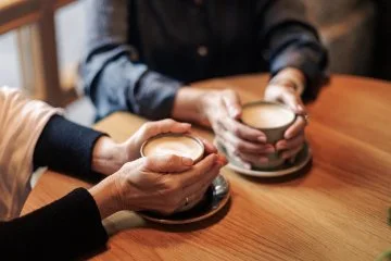 Two cups of coffee being held