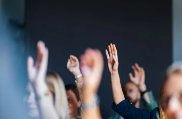 People in a room putting their hands up