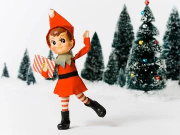 A Christmas elf holding a gift in snow