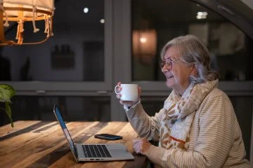 Lady holding mug in front of laptop