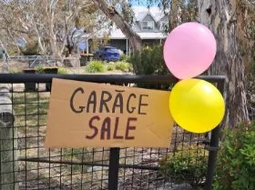 Balloons and a garage sale sign on the gate of a rural property