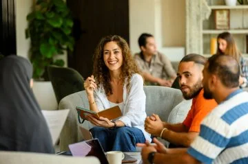 A smiling woman sits with other people