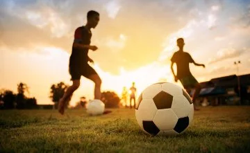 Young people playing soccer with a sunset in the background