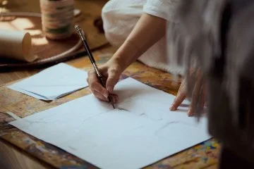 A person sitting on a floor doing a life drawing