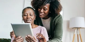 A senior and their daughter using a computer