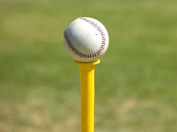 A white teeball sitting atop a yellow pin
