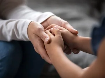 An older persons hands cradling a younger persons hands