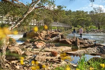 Two people stand on rocks beside the Bells Rapids bridge