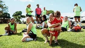 Woman playing In club soccer tournament giving daughter a hug on the sidelines