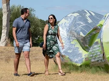 A couple walk past a large sculpture of a crushed drink can