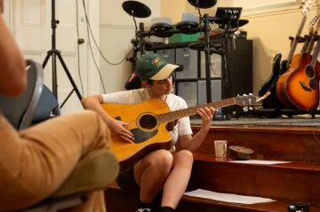 girl sitting down playing acoustic guitar