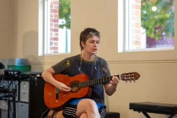 a girl singing and playing an acoustic guitar