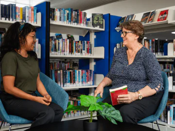 Two people in a library talking