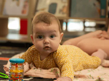 A baby in a library space with sensory toys