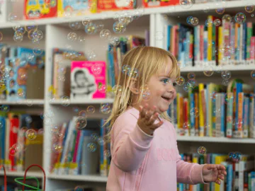 A young person smiling with bubbles in a library
