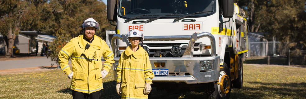 Three female firefighters standing in front of a vehicle