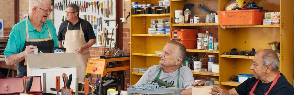 Older men at a men's shed working on wood work projects