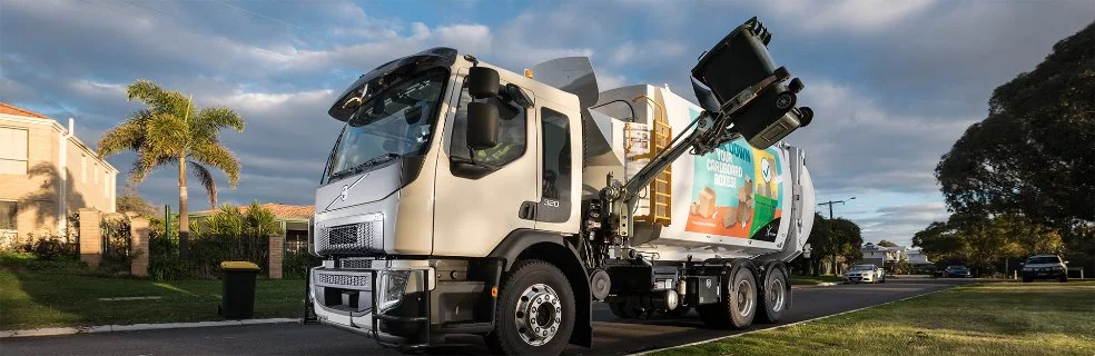 A rubbish truck emptying a bin on a suburban street