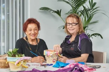 An elderly lady doing craft activity with a Community care staff member