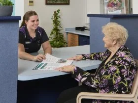 A older woman sitting at the reception desk at Community Care