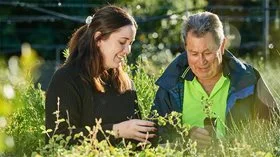 A volunteer and a City resident look at saplings at Trillion Trees